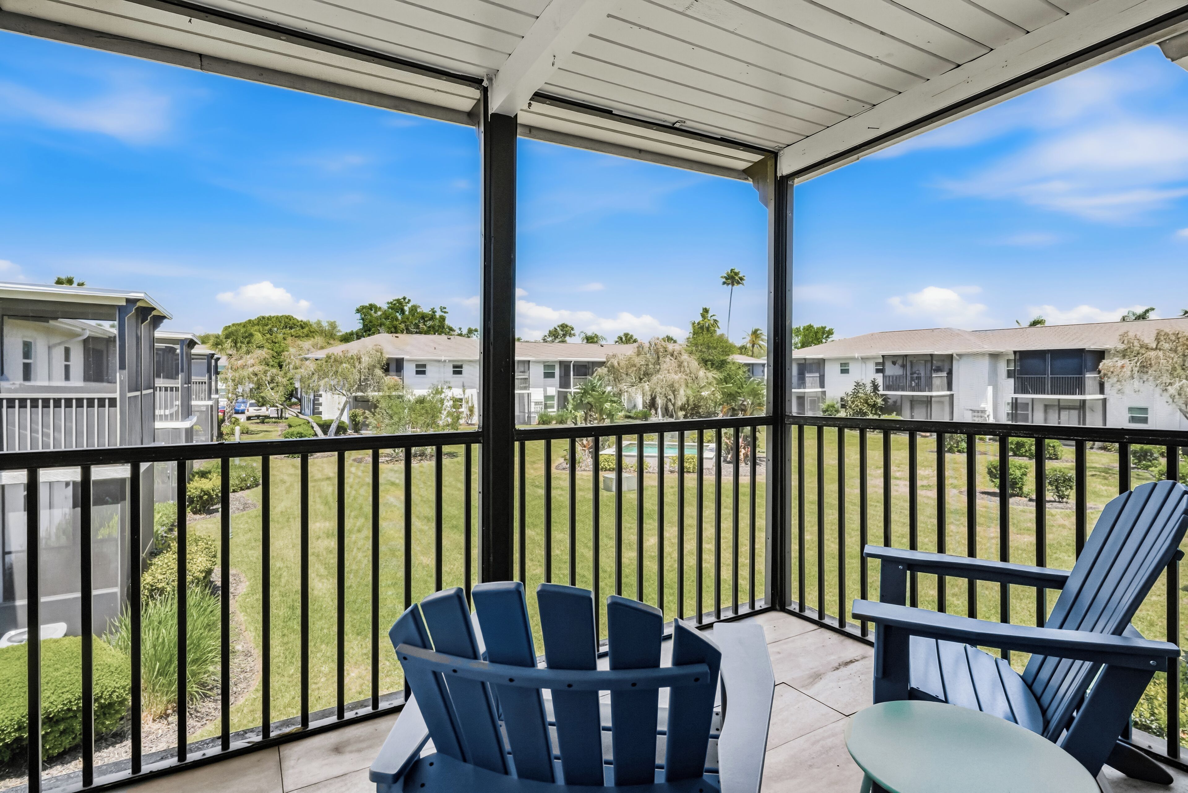 A covered balcony with two Adirondack chairs and a view of neighboring houses.