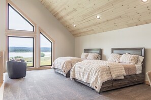 A bedroom with two beds, a large window with a view of a lake, and a wooden ceiling. - The Lodge at Beach Meadow | Hot Tub + Pickleball (Island Park)