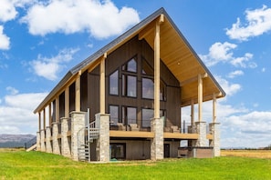 Ein großes, modernes Blockhaus mit geräumiger Terrasse und Steinsäulen.