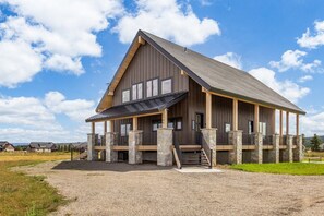 A large, single-story building with a prominent gable roof, multiple windows, and a covered porch area. - The Lodge at Beach Meadow | Hot Tub + Pickleball (Island Park)