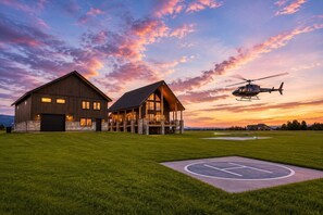 Ein großes, zweistöckiges Gebäude mit einer überdachten Veranda und einem Hubschrauber im Hintergrund.