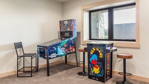 Ett rum med ett arkadspelbord med Star Wars-tema, ett fönster och ett litet bord med ett Pac-Man-spel.