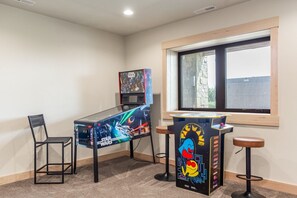 Ein Zimmer mit einem Star Wars Spielautomaten, einem Fenster und einem kleinen Tisch mit Pac-Man.