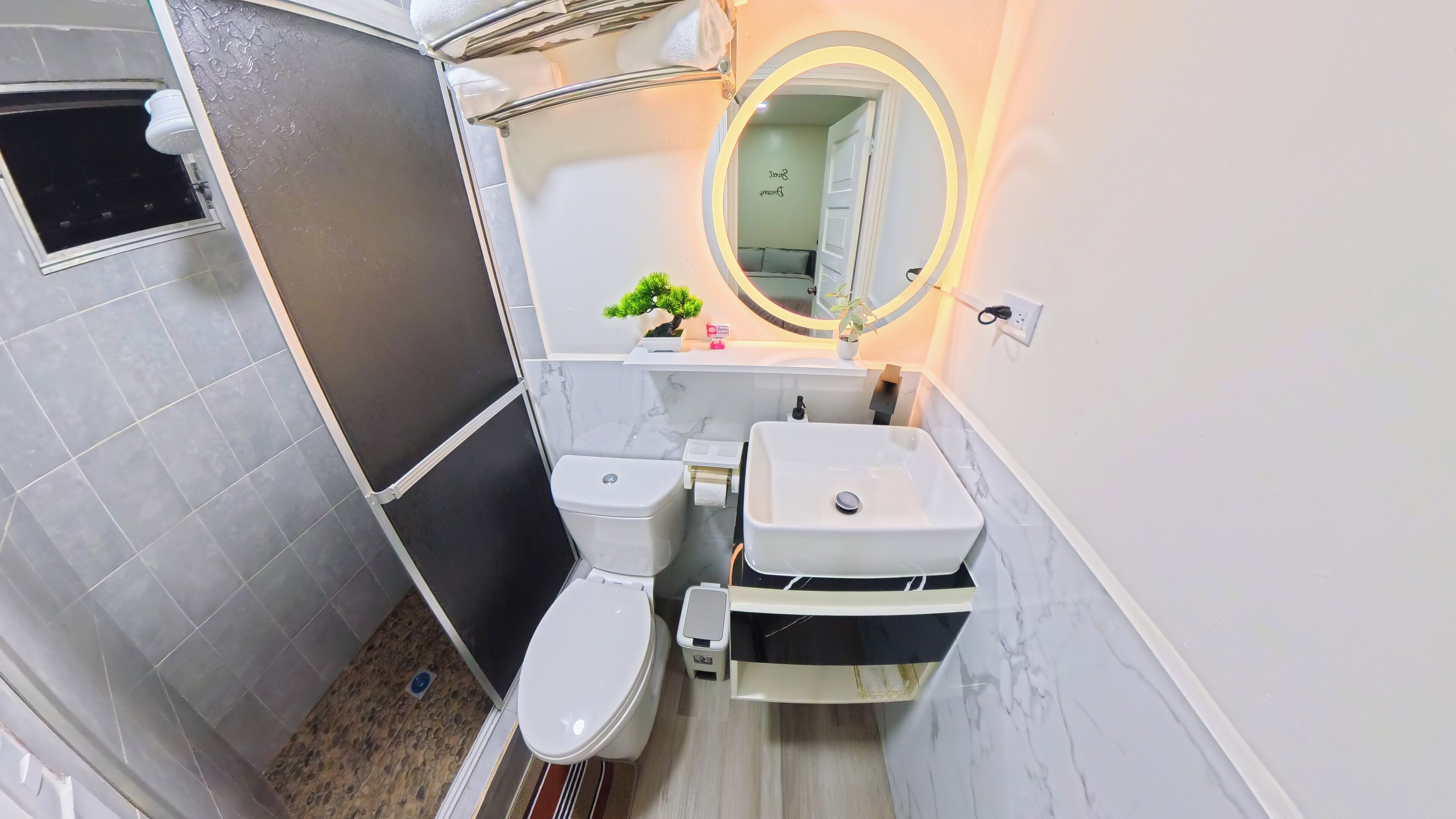 Et badeværelse med toilet, vask og bruseområde.