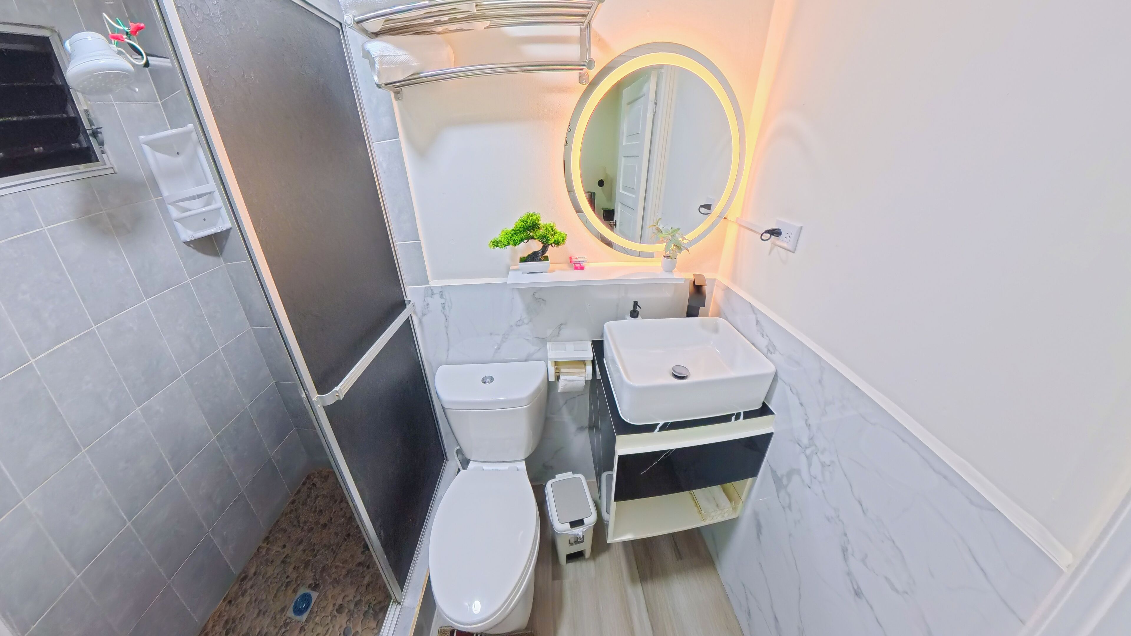 A compact bathroom with a toilet, sink, and shower.