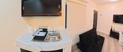 A modern kitchen with a built-in microwave, a sink, and a black chair.
