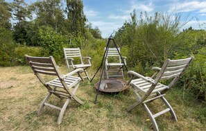 Four wooden chairs arranged in a circle with a metal chair swing in the center, set in a grassy outdoor area with trees in the background. - Awesome home in Knebel with WiFi (Knebel)