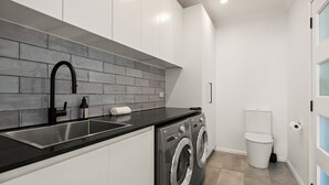 Eine moderne Küche mit schwarzer Arbeitsplatte, Edelstahl-Spüle und einer grauen Backspülwand.