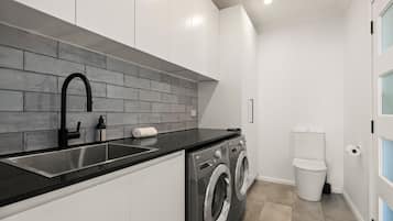 A modern kitchen with a black countertop, stainless steel sink, and a grey brick backsplash.