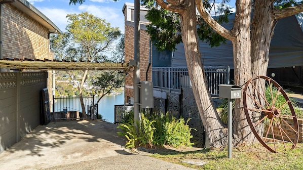 A residential property with a brick house, a metal gate, a tree, and a mailbox.
