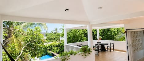 Varanda ampla com rede, piscina e área de refeições com cadeiras e mesa.