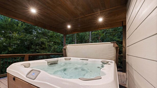 A hot tub with a control panel, surrounded by a wooden deck and a covered area with a wooden ceiling. - 5BR Hochatown Cabin: Hot Tub - Game Room - Fits 13 - Min to Lake & Casino (Broken Bow)