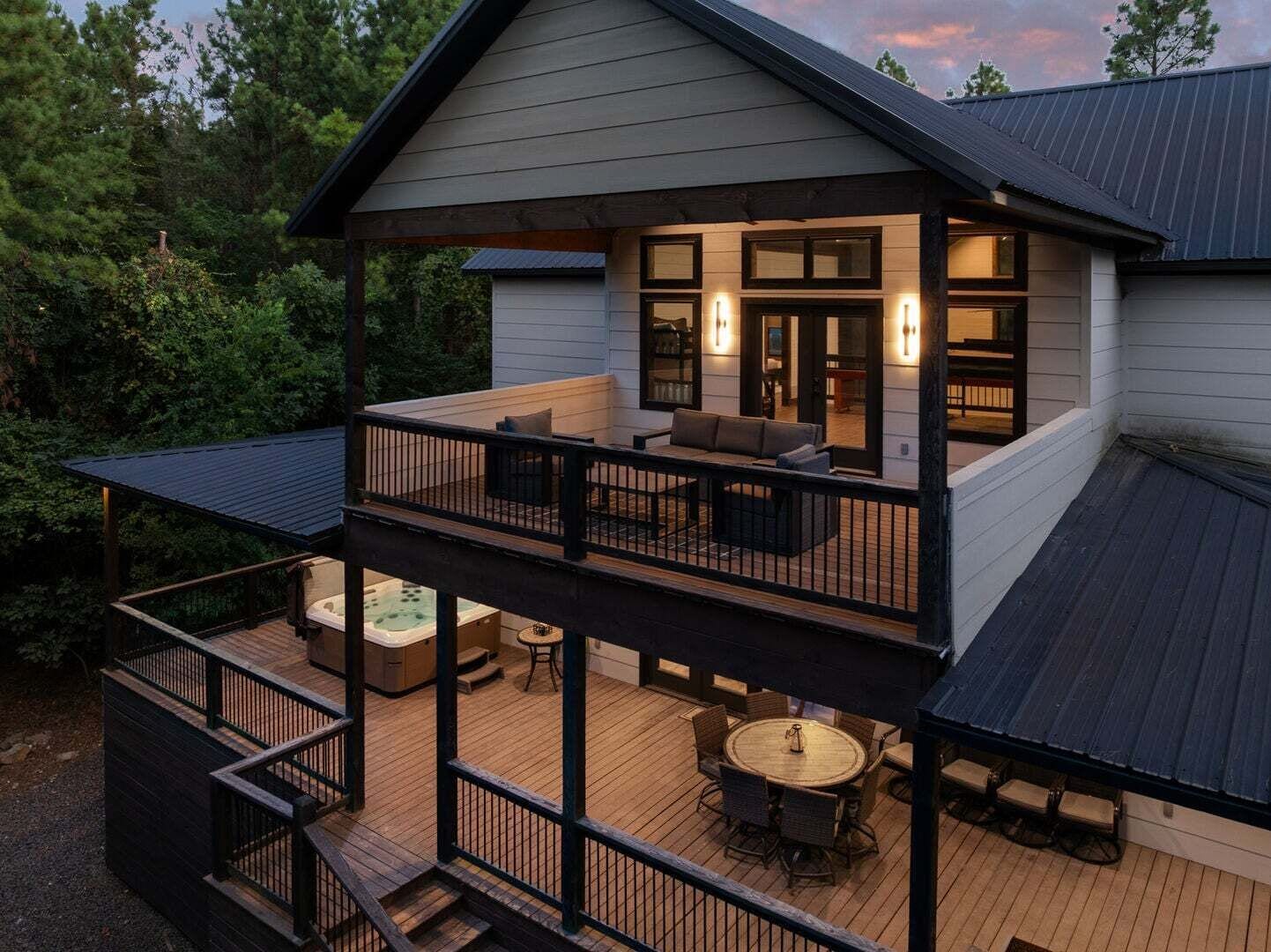 A two-story house with a balcony, a hot tub, and outdoor seating.