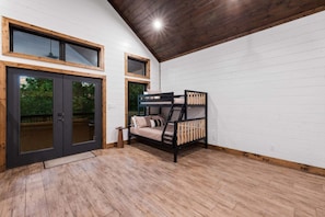 A room with a bunk bed, a sliding glass door leading outside, and a wooden ceiling. - 5BR Hochatown Cabin: Hot Tub - Game Room - Fits 13 - Min to Lake & Casino (Broken Bow)