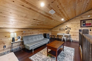 A cozy cabin interior with a sofa, a small table, a desk, and a chair. - Hochatown Luxury Cabin on 1+ Acre: Main Lodge + Detached Private Suite & Stream (Broken Bow)