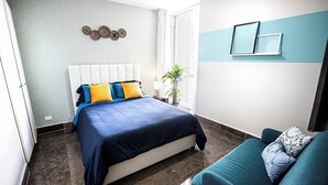 Una camera da letto con un letto, un divano, una pianta in vaso e una parete con piatti decorativi.