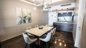 Un'area pranzo moderna con un tavolo grande, sei sedie e un lampadario contemporaneo.