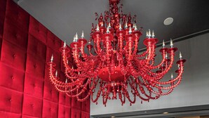 Una parete imbottita rossa, un lampadario rosso e sedie rosse attorno a un tavolo in una stanza.