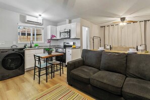 Um espaço compacto com cozinha americana, área de refeições e sala de estar com sofá.