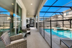 Un espace piscine extérieur moderne, doté de parois en verre, de mobilier en osier et offrant une vue dégagée sur le ciel.