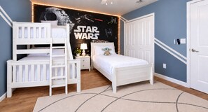 A bedroom with a Star Wars themed wall, a bunk bed, a single bed, a nightstand, and a door. - Walk to Lazy River - Themed 6BR Home - Private Pool, Spa and Game Room, Store... (Kissimmee)