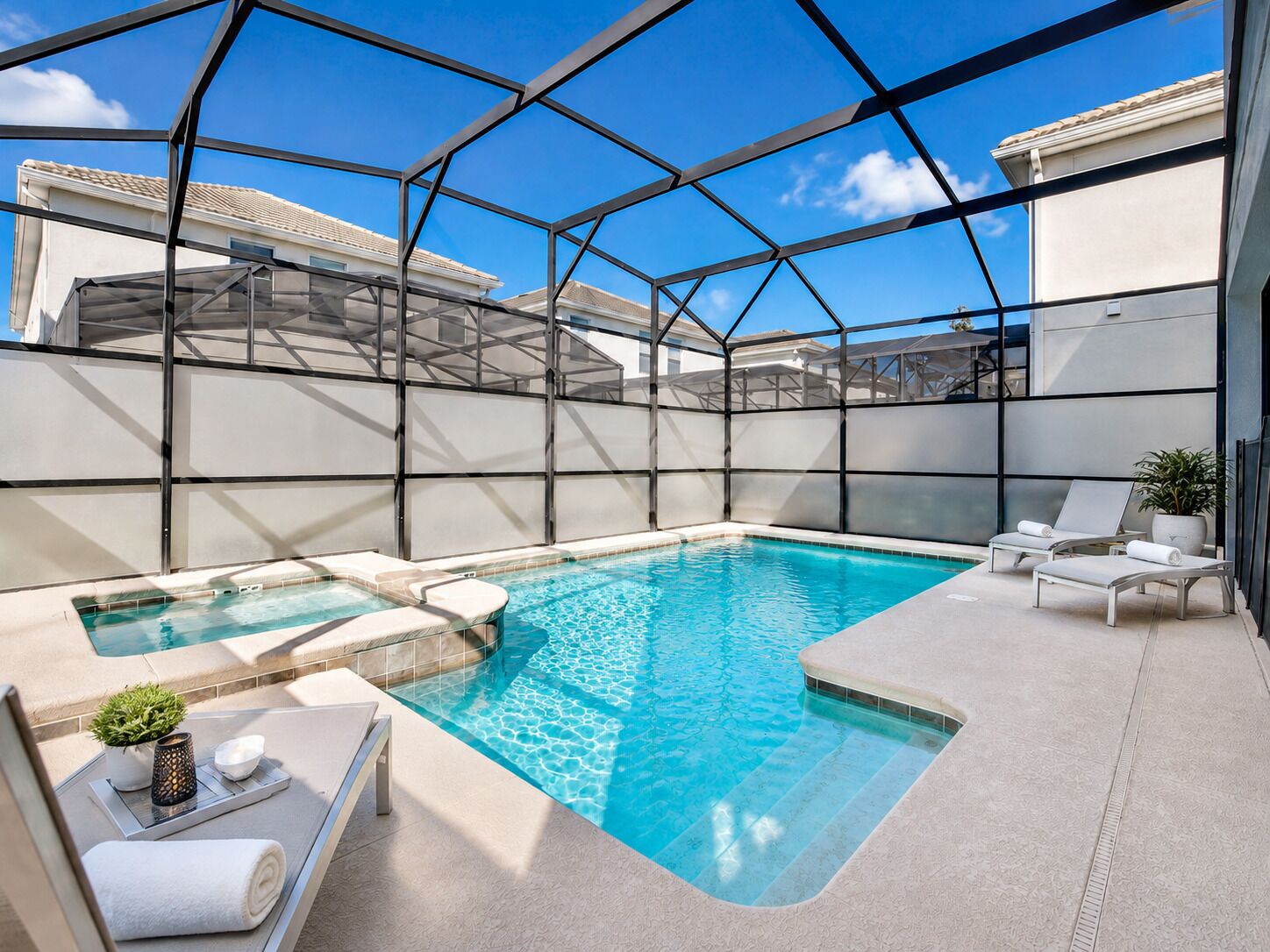 Ein Dachpool mit Glasverkleidung, Liegestühlen und einem kleinen Tisch mit Pflanze und Kerze.