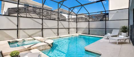 Piscina en la azotea con cerramiento de vidrio, sillas de descanso y una mesa pequeña con una planta y una vela.