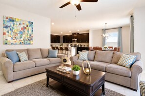 Un salon moderne avec deux canapés, une table basse et un ventilateur de plafond.