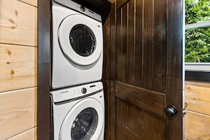 Una sala de bugaderia amb dues rentadores apilades, parets de fusta i una porta.