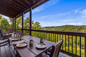 Eine Holzterrasse mit Tisch für zwei Personen, mit Blick auf eine bewaldete Landschaft.