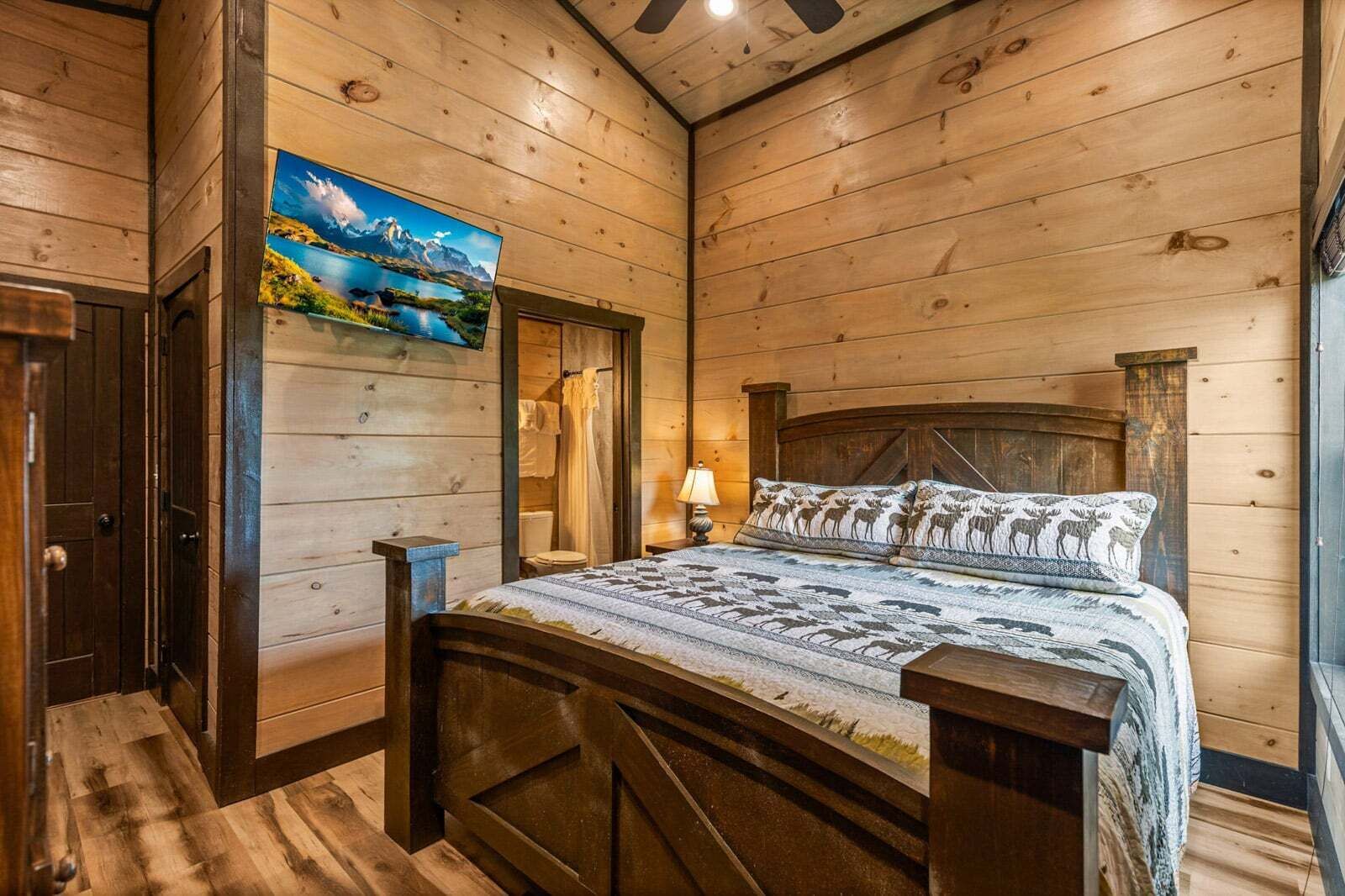 A wooden cabin-style bedroom with a bed, a painting, and a wooden door.