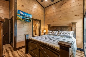 Ein schlicht eingerichtetes Schlafzimmer im Chalet-Stil mit einem Bett, einem Gemälde und einer Holztür.