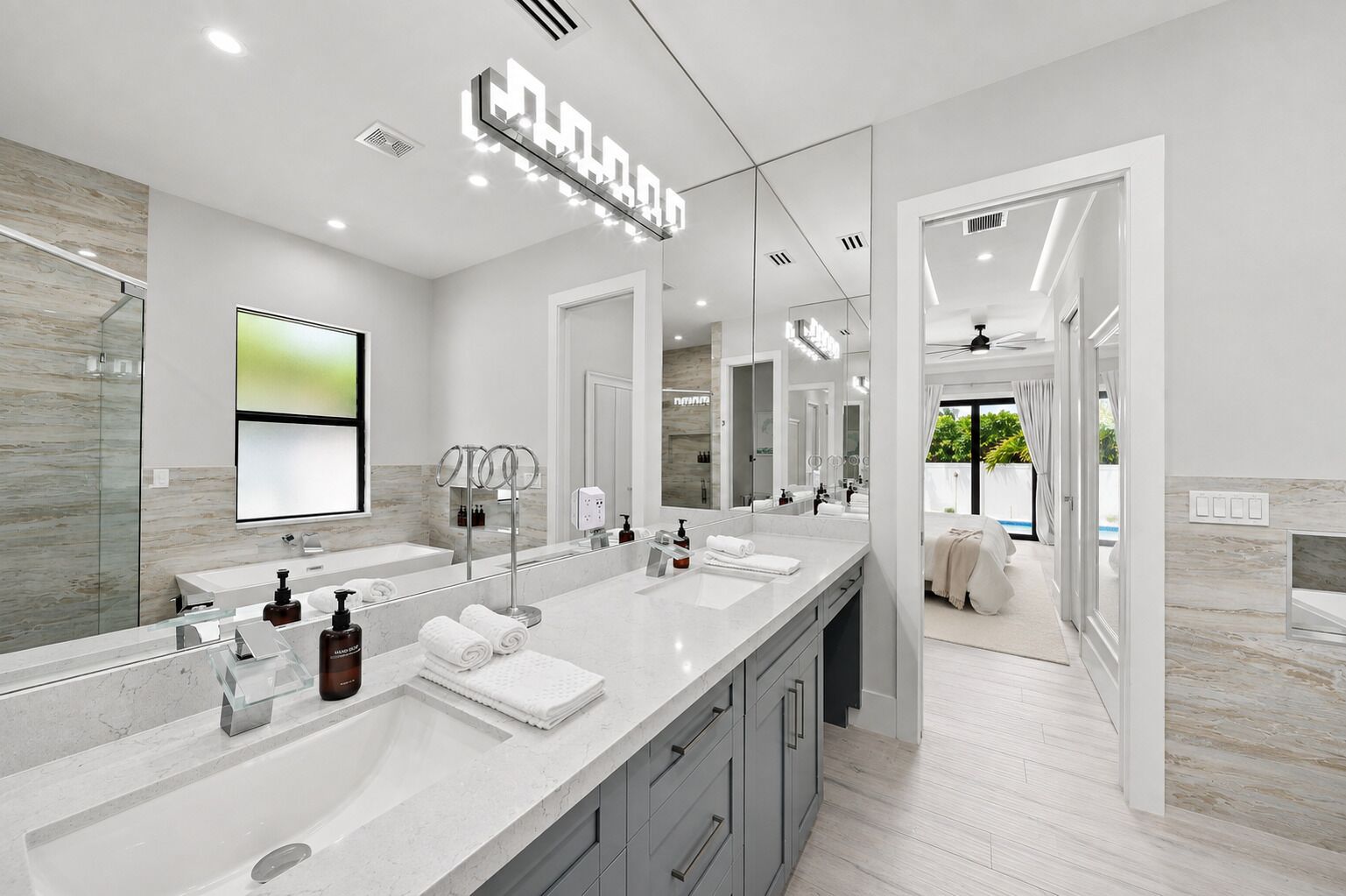 Une salle de bain moderne avec un grand miroir, un meuble-lavabo et un espace douche.