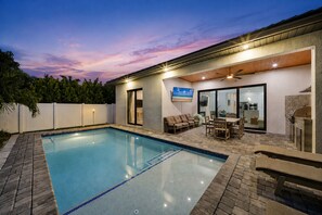 Un jardin avec une piscine, un espace salon extérieur et un coin barbecue.