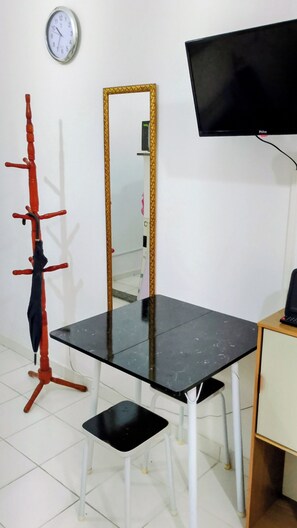 A room with a black table, a white chair, a red coat rack, a wall-mounted TV, and a clock. - Apartment on Copacabana Beach (Rio de Janeiro)