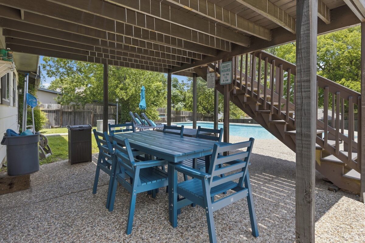 Ein überdachter Außenbereich mit Pool, Tisch und Stühlen sowie einer Treppe.