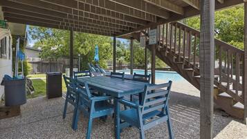 A covered outdoor area with a pool, a table and chairs, and a staircase.