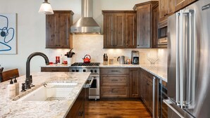 A modern kitchen with wooden cabinets, stainless steel appliances, and a marble countertop. - Winter Park Resort Villa 509 I Hot Tub I Great View I Theatre I Fire Table I Discounted Attractions (Winter Park)