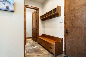 Ein Flur mit einer Holzbank, einer Tür und einem an der Wand befestigten Regal.