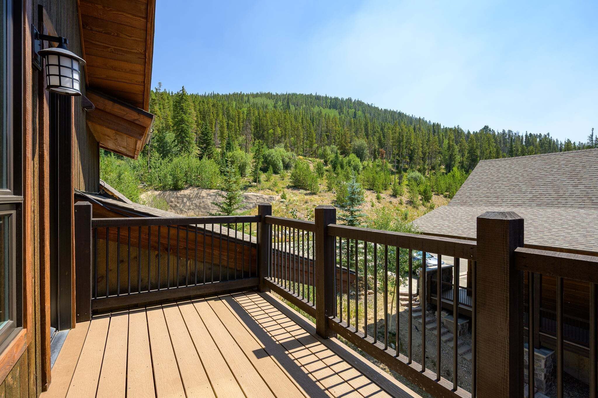 A wooden deck with a railing overlooking a forested hillside.