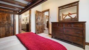 A bedroom with a bed, a dresser, a mirror, and a door leading to another room. - Winter Park Resort Villa 509 I Hot Tub I Great View I Theatre I Fire Table I Discounted Attractions (Winter Park)