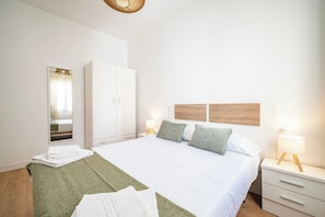Quarto de hotel com cama, guarda-roupa, espelho e abajures.