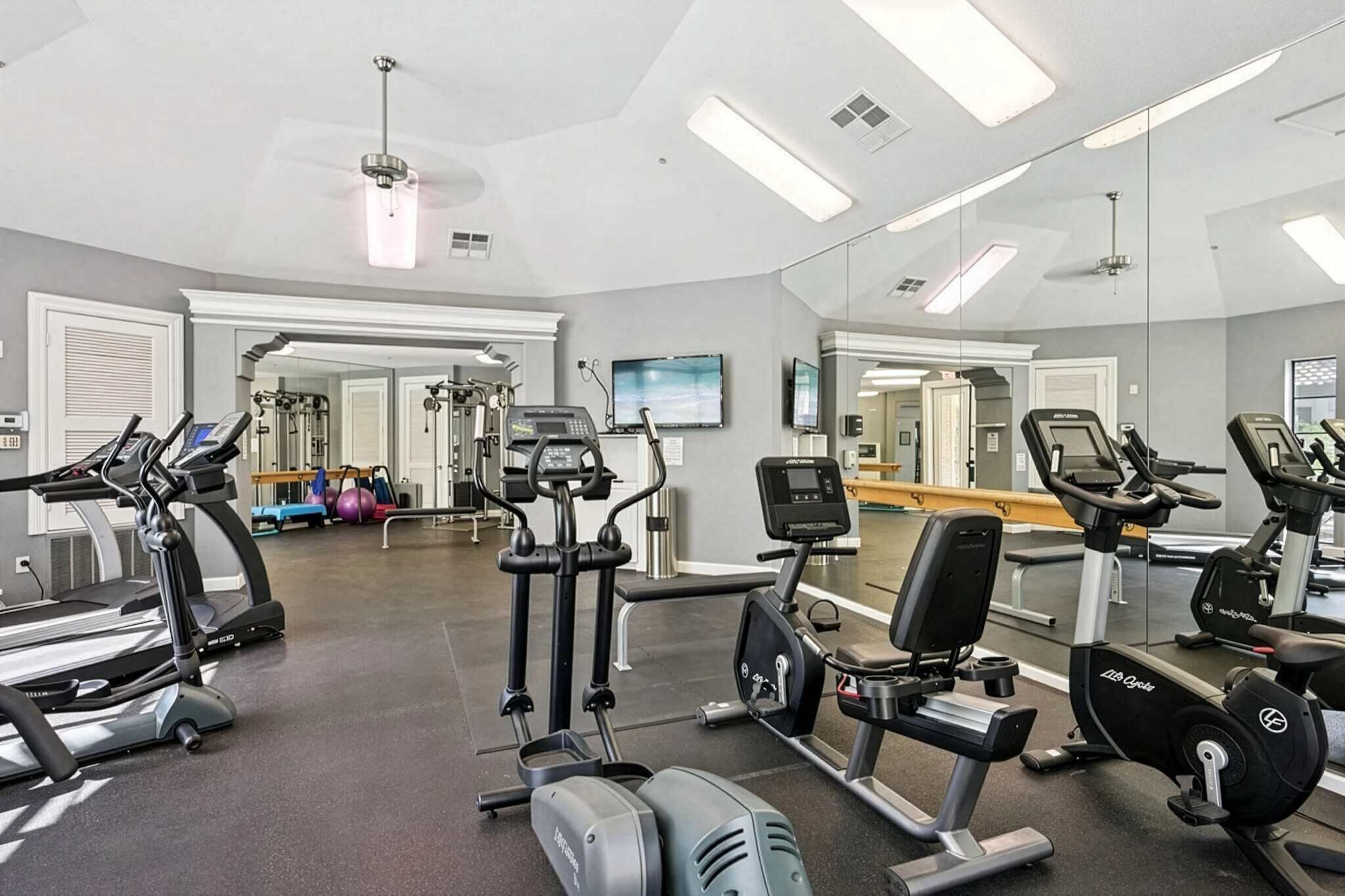 Uma academia com esteiras, elípticos e equipamentos de musculação.