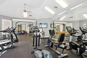 Une salle de sport équipée de tapis de course, de vélos elliptiques et d'appareils de musculation.