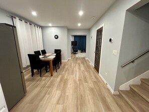 A modern kitchen with a refrigerator, a dining area with a table and chairs, and a staircase leading to another level. - Waterfront Views! Steps to Caesars & Downtown (Windsor)