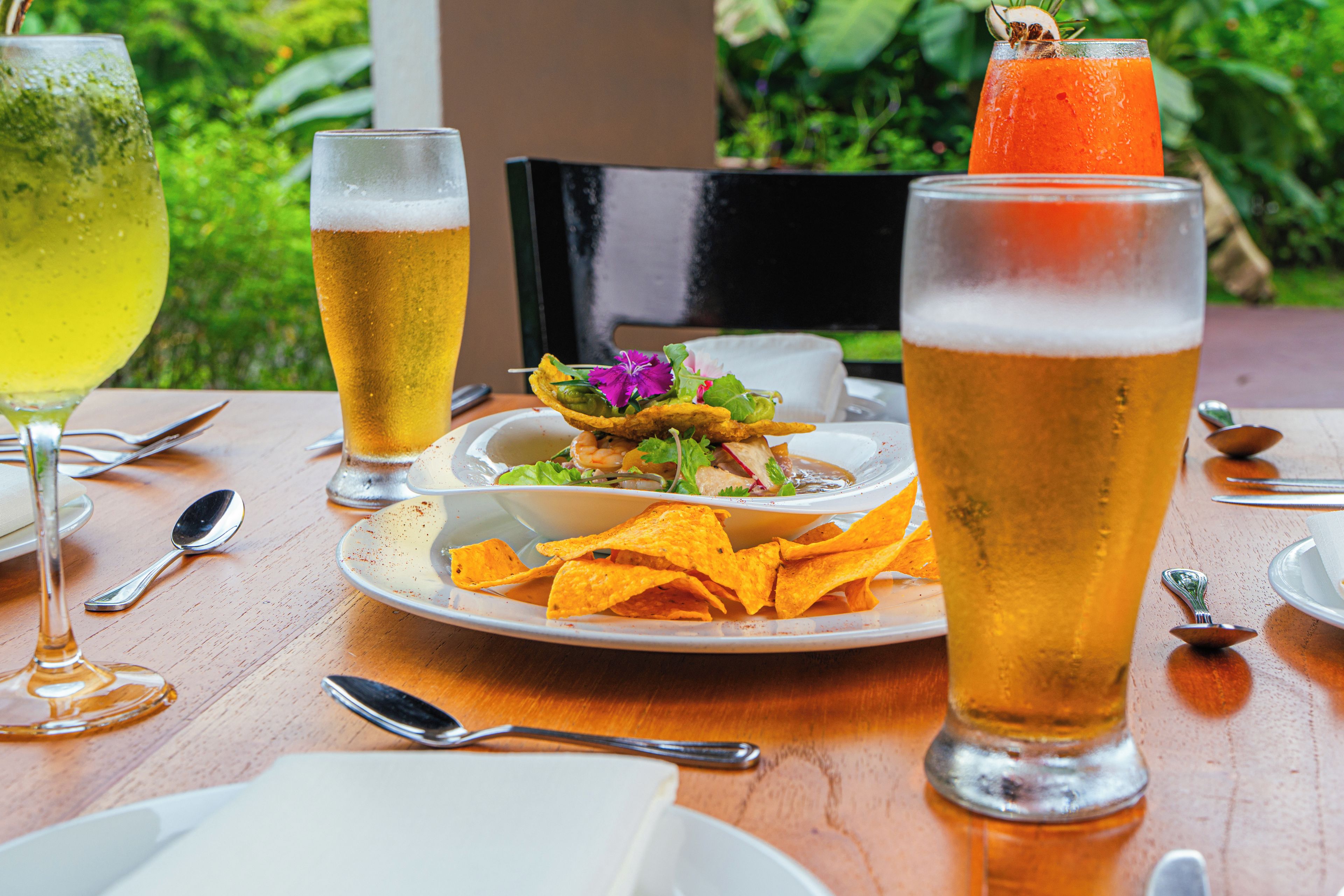 Una mesa con comida y bebidas, incluyendo un plato de papas fritas, un tazón de ensalada y dos vasos de cerveza.