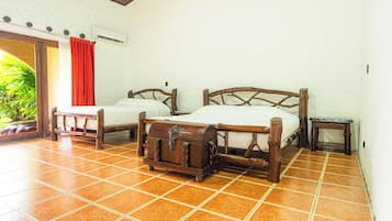 A room with two wooden beds, a red curtain, an air conditioning unit, and a tiled floor.
