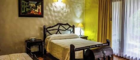 A single bed with a headboard, a bedside table with a lamp, a wall-mounted air conditioner, and a window with curtains.