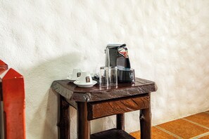 A small wooden table with a coffee maker, a cup, and glasses. - Arenal Rainforest (La Fortuna)