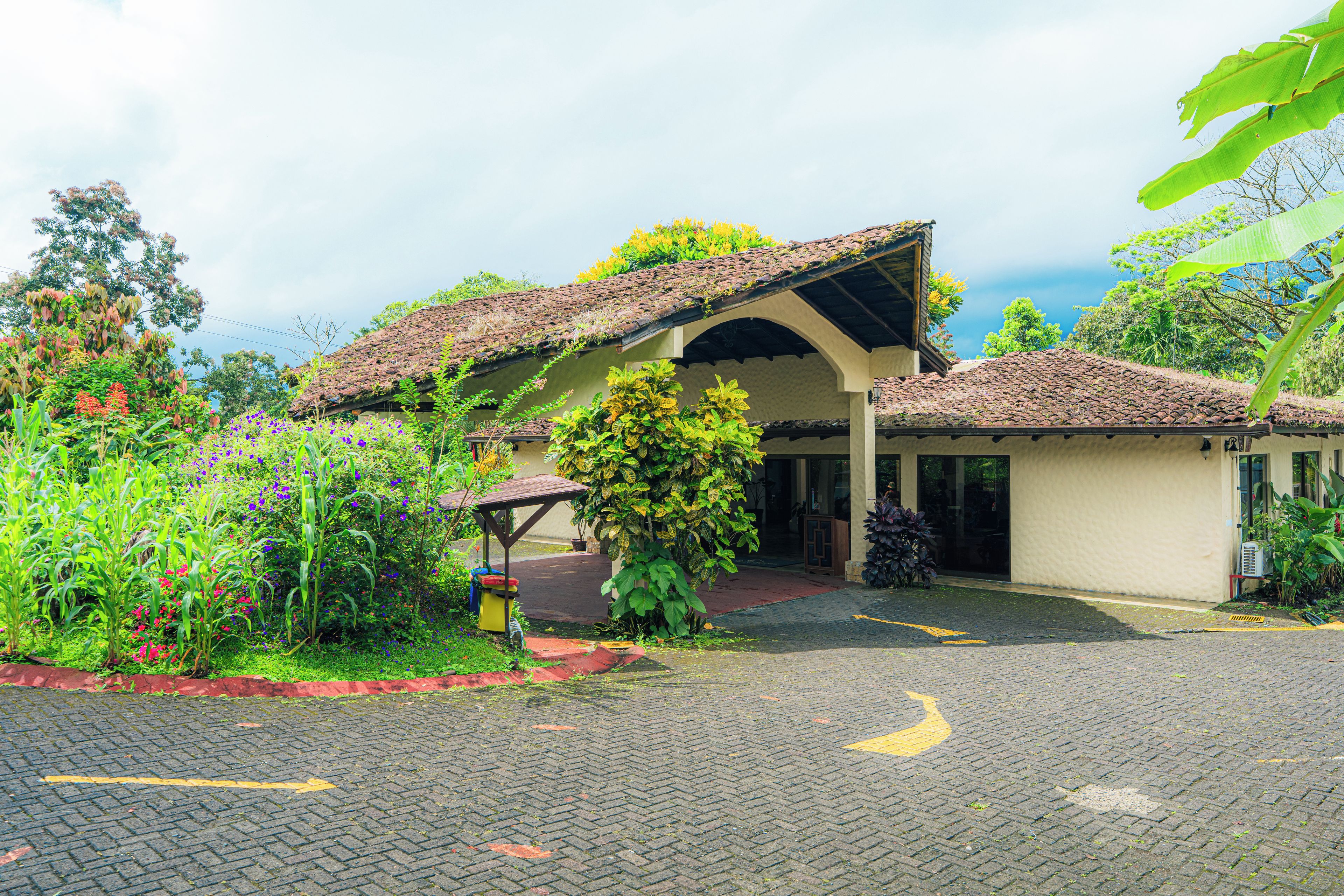 A building with a tiled roof, a covered entrance, and a paved driveway.